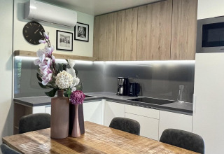 Cuisine moderne dans la lodge Domus à Poort van Maastricht, Pays-Bas, avec table en bois et fleurs décoratives.
