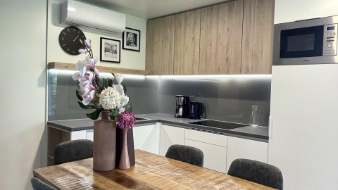 Cuisine moderne dans la lodge Domus à Poort van Maastricht, Pays-Bas, avec table en bois et fleurs décoratives.