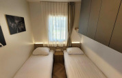 A bright twin room at Domus lodge, Poort van Maastricht, with two single beds, window, art, and storage.