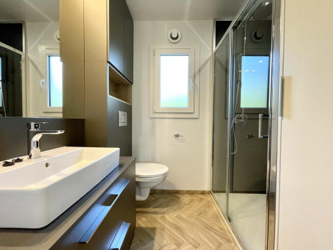 Baño moderno en el alojamiento glamping Domus, con ducha, lavabo y ventana con luz natural.