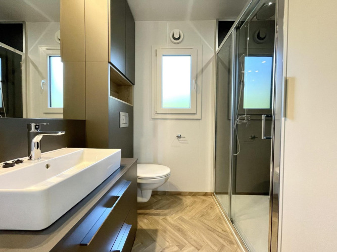 Baño moderno en el alojamiento glamping Domus, con ducha, lavabo y ventana con luz natural.
