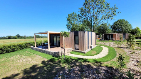 Foto van de Domus lodge bij Poort van Maastricht in Nederland, omgeven door groen en moderne huisjes.
