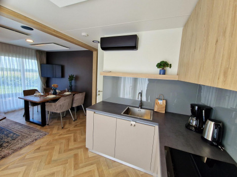 Modern tiny house kitchen and dining area inside Domus at Poort van Maastricht, Netherlands, with wood floor.