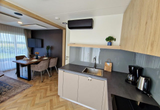 Cuisine moderne et salle à manger d'une tiny house Domus à Poort van Maastricht, Pays-Bas, avec sol en bois.