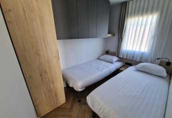 Kleine slaapkamer in Domus tiny house bij Poort van Maastricht, met twee eenpersoonsbedden en raam.