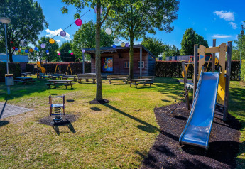 Kleurrijke speeltuin met glijbaan en schommels bij Domus tiny house, Poort van Maastricht, Nederland.