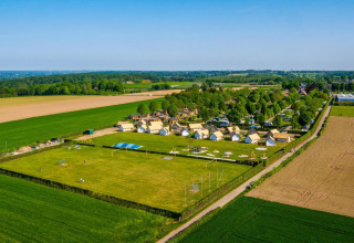 Vue aérienne de tiny houses et camping à Poort van Maastricht, Pays-Bas, entourés de champs verdoyants.