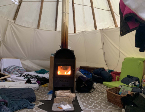 Interno della tenda Tipi presso Buytenplaets Suydersee, Paesi Bassi, con stufa e attrezzi da campeggio.