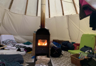 Innenansicht eines Tipi-Zeltes bei Buytenplaets Suydersee, Niederlande, mit Ofen und Schlafsäcken.