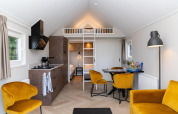 Moderne Mountain Lodge-stue på Resort Mooi Bemelen med gule stole, tekøkken og hems, Holland.