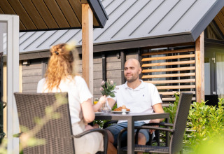 Dos personas desayunando al aire libre en Mountain Lodge, Resort Mooi Bemelen, Países Bajos, mañana soleada.