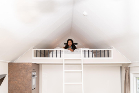 Mujer relajándose en la cama altillo de Mountain Lodge en Resort Mooi Bemelen, Países Bajos, ambiente acogedor.