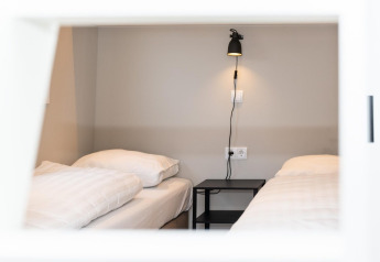 Moderne lodge-slaapkamer met twee eenpersoonsbedden, zwarte wandlamp en nachtkastje bij Mountain Lodge, Resort Mooi Bemelen.