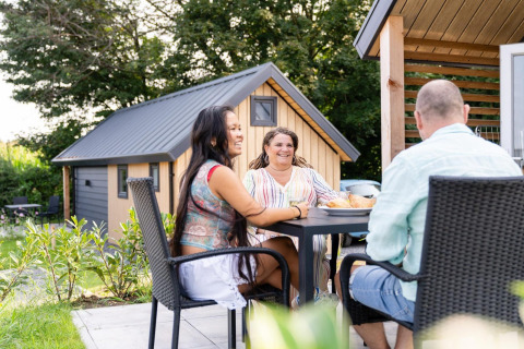 Drei Personen sitzen entspannt draußen am Tisch bei der Mountain Lodge im Resort Mooi Bemelen, Niederlande.