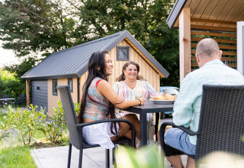 Drei Personen sitzen entspannt draußen am Tisch bei der Mountain Lodge im Resort Mooi Bemelen, Niederlande.