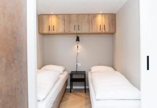 Dos camas individuales con sábanas blancas en una habitación de Mountain Lodge en Resort Mooi Bemelen, Países Bajos.