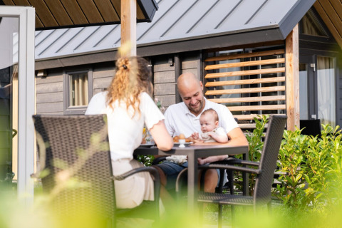 Eine Familie sitzt fröhlich auf der Terrasse der Mountain Lodge im Resort Mooi Bemelen in den Niederlanden.
