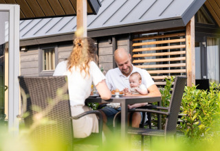 Een familie geniet samen op het terras van de Mountain Lodge bij Resort Mooi Bemelen in Nederland.