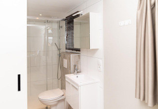 Moderne badkamer in Mountain Lodge aan Resort Mooi Bemelen, Nederland, met douche, toilet en lavabo.