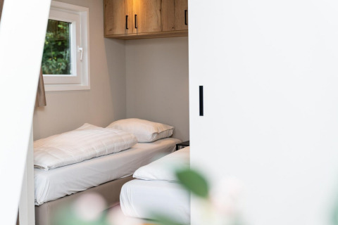 Soveværelse med to enkeltsenge, hvidt sengetøj og vindue i Mountain Lodge på Resort Mooi Bemelen.