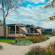 To moderne Tiny Court-lodges med overdækkede terrasser i ferieparken De Boshoek i Holland, omgivet af planter.