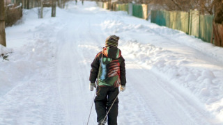 Un niño arrastra un trineo por una carretera nevada en un parque vacacional con alojamientos glamping.