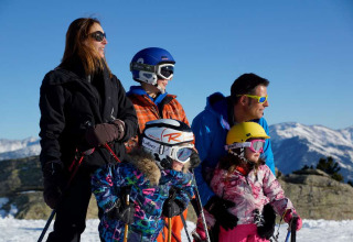 Familie beim Skifahren im Les Chalets Huttopia de Font-Romeu, umgeben von verschneiten Bergen.