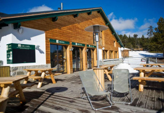 Terrasse extérieure avec tables en bois aux Chalets Huttopia de Font-Romeu, parc de vacances en Occitanie, France.