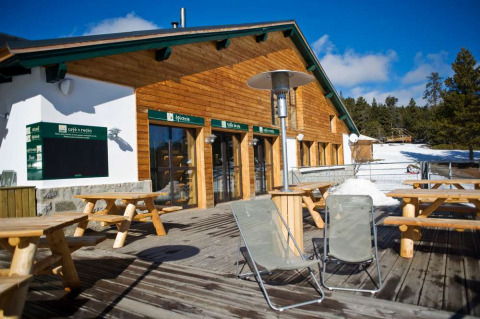 Terraza exterior con bancos de madera en Les Chalets Huttopia de Font-Romeu, situado en Occitanie, Francia.