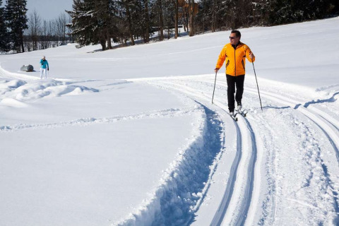 Deux personnes font du ski de fond dans la neige aux Chalets Huttopia de Font-Romeu en Occitanie, France.