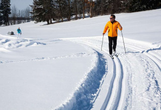 Deux personnes font du ski de fond dans la neige aux Chalets Huttopia de Font-Romeu en Occitanie, France.