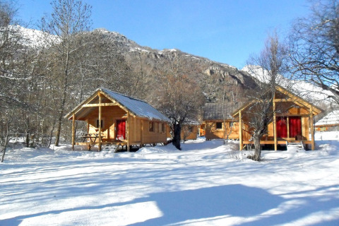 Sneeuw bedekte houten chalets bij Les Chalets Huttopia de Vallouise, omgeven door bergen in Frankrijk.