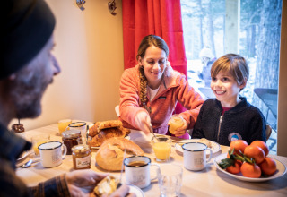 Family enjoying breakfast together at a table in Les Chalets Huttopia de Vallouise, Provence-Alpes-Côte d’Azur, France.