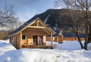 Chalets en bois aux Chalets Huttopia de Vallouise, Provence-Alpes-Côte d’Azur, entourés de neige et de montagnes.