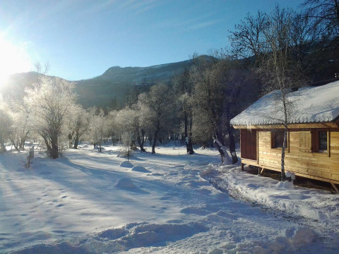 Houten chalet in besneeuwd landschap met zonlicht en bevroren bomen in Vallouise, Provence-Alpes, Frankrijk.
