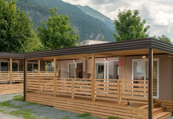 Gemütliches Ferienhaus mit Holzveranda und Bergblick, umgeben von Bäumen und Natur.