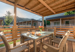 Überdachte Holzterrasse mit Esstisch und Stühlen im Cottage Hermagor-Nassfeld, Österreich, mit Bergblick.
