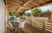 Træterrasse med spisebord ved Cottage på Hermagor-Nassfeld, Østrig, omgivet af grønne træer.