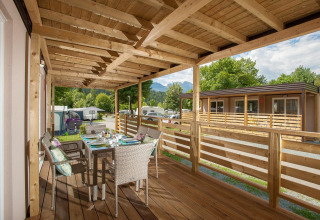 Træterrasse med spisebord ved Cottage på Hermagor-Nassfeld, Østrig, omgivet af grønne træer.