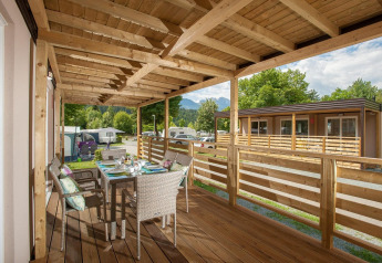 Træterrasse med spisebord ved Cottage på Hermagor-Nassfeld, Østrig, omgivet af grønne træer.