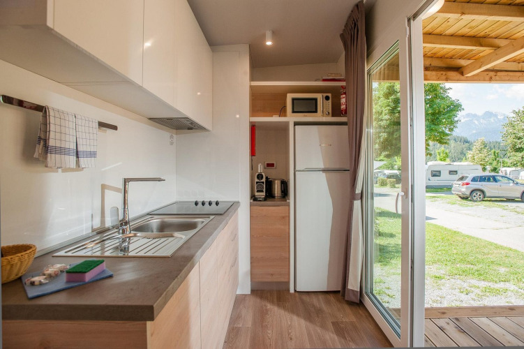 Modern kitchen inside a cottage at Hermagor-Nassfeld, Austria, with view of campground and mountains.