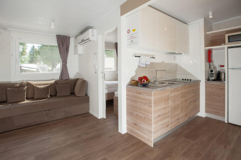 Sala de estar y cocina modernas dentro de una cabaña en Hermagor-Nassfeld, Austria, con sofá marrón.
