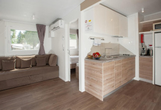 Sala de estar y cocina modernas dentro de una cabaña en Hermagor-Nassfeld, Austria, con sofá marrón.