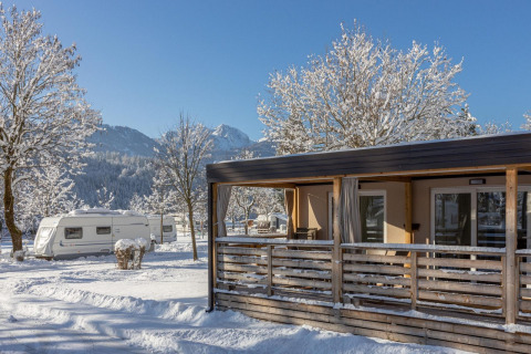 Cabaña y caravanas nevadas en Cottage en Hermagor-Nassfeld, Austria, con montañas al fondo en invierno.