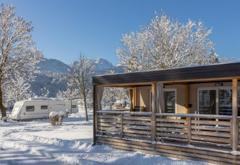 Cabaña y caravanas nevadas en Cottage en Hermagor-Nassfeld, Austria, con montañas al fondo en invierno.
