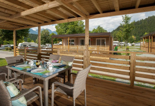 Udendørs spiseområde på en træterrasse i Cottage at Hermagor-Nassfeld, med udsigt til bjerge og grønne omgivelser.