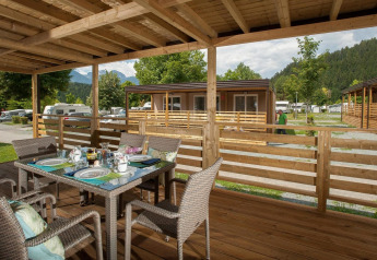 Udendørs spiseområde på en træterrasse i Cottage at Hermagor-Nassfeld, med udsigt til bjerge og grønne omgivelser.