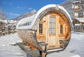 Traktorcabine ved Hermagor-Nassfeld lodge i Østrig, dækket af sne, omgivet af bjerge og blå himmel.