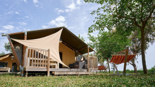 Safari-Zelt Villatent Wood auf Camping Nautic Almata in Spanien, Terrasse und Hängematte unter Bäumen.