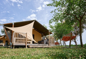 Tente safari Villatent Wood au Camping Nautic Almata en Espagne, terrasse en bois et hamac sous les arbres.